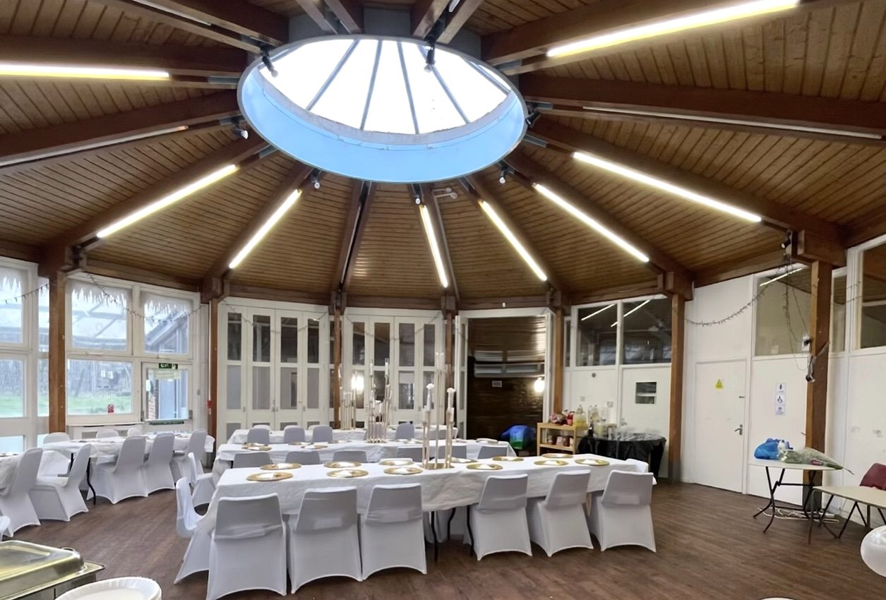 Hall set for a seated reception with white chair covers and gold place settings